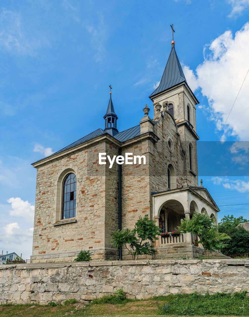 Cloudy landscape with stone church. catholic church on background of cloudy sky.