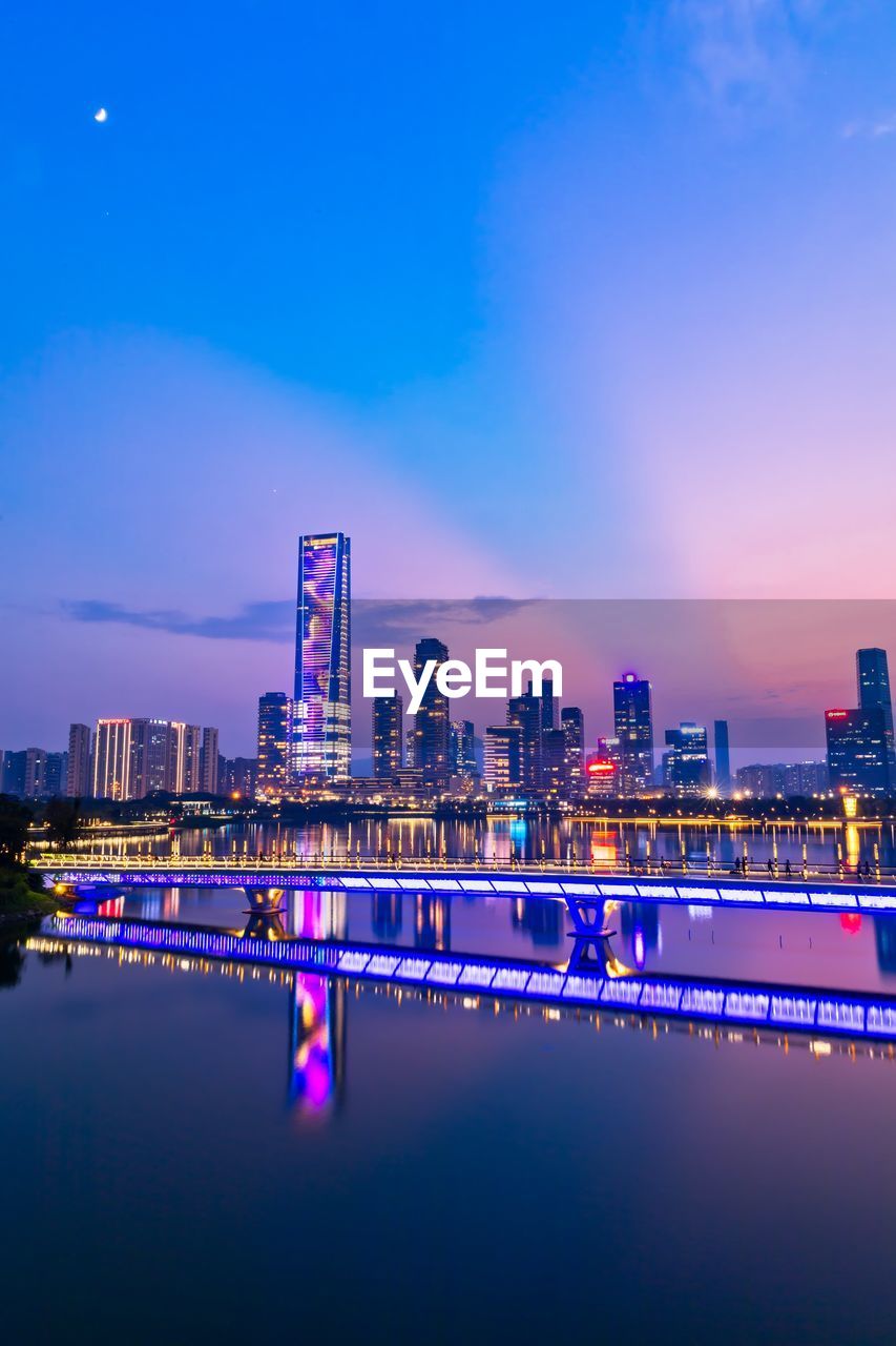 Illuminated buildings against blue sky at night