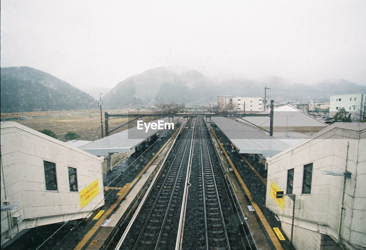 Railroad tracks by mountain against sky