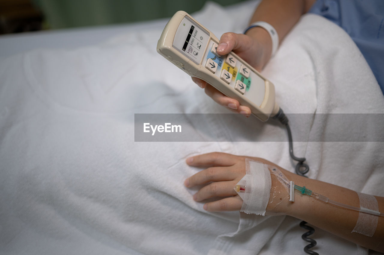 adult, indoors, hand, one person, women, healthcare and medicine, technology, bed, finger, furniture, wireless technology, holding, communication, skin, lifestyles, female, limb, hospital, smartphone, portable information device, mobile phone, relaxation, close-up, domestic room