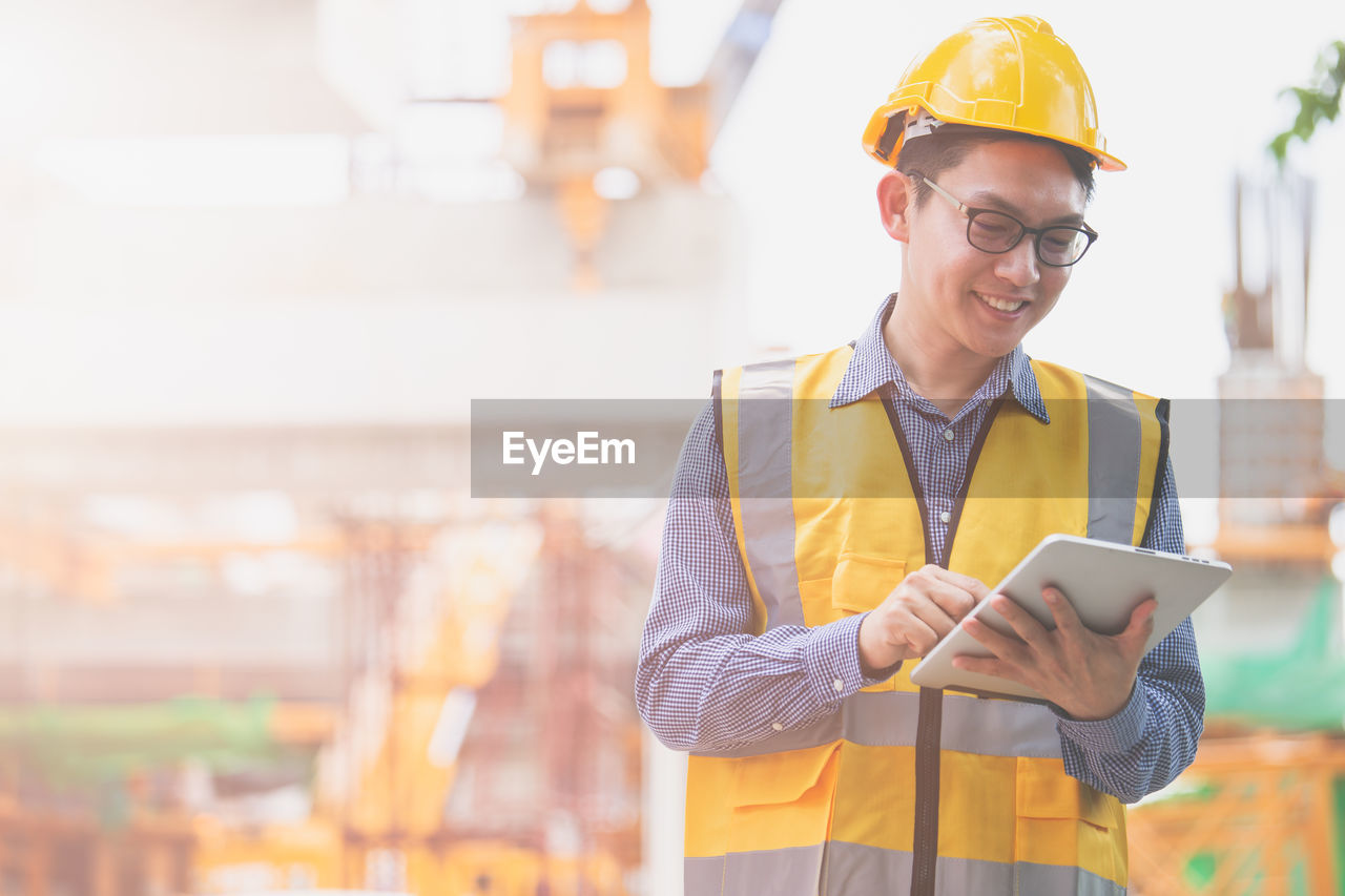 Architect using digital tablet while standing at construction site