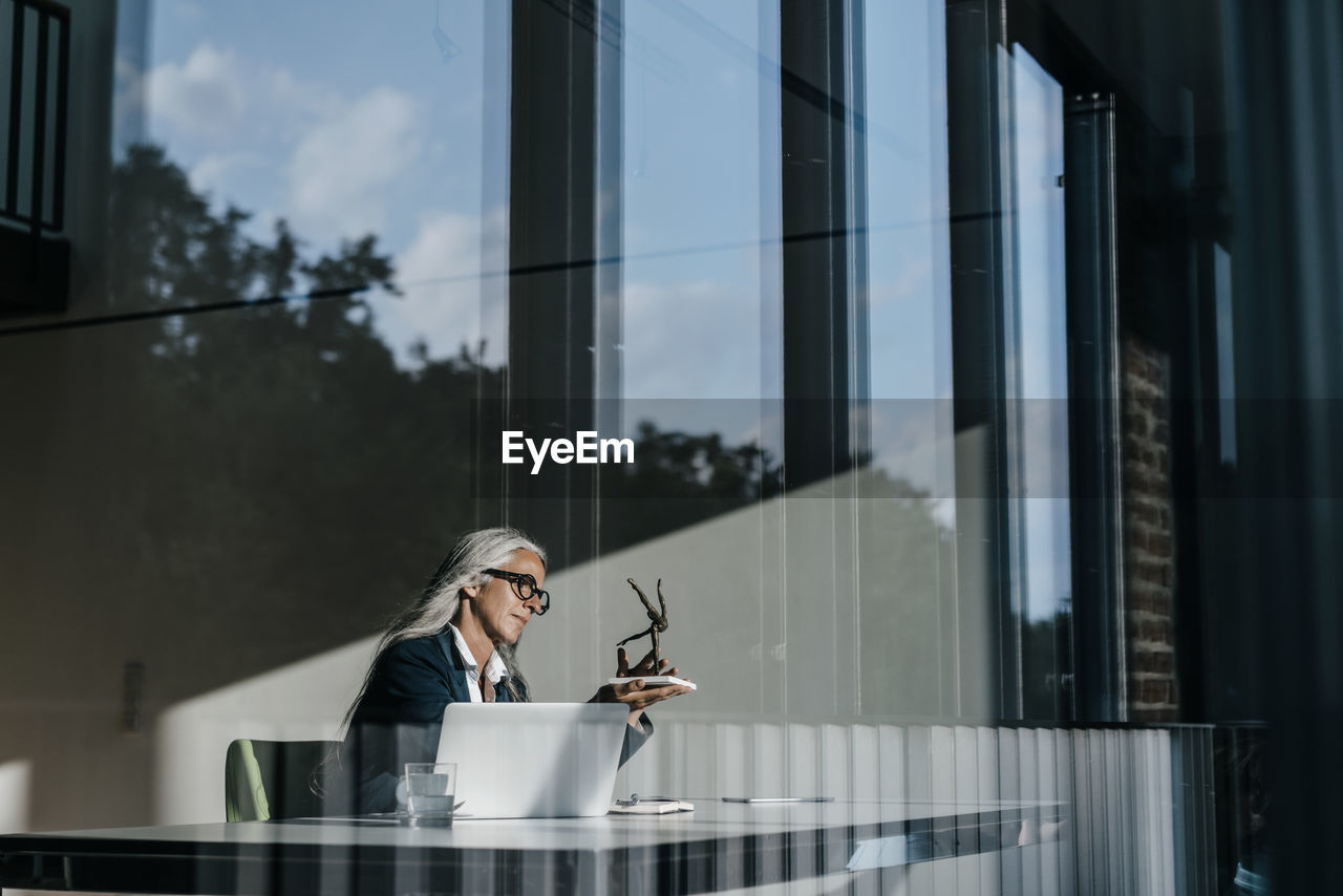 Businesswoman at desk looking at sculpture