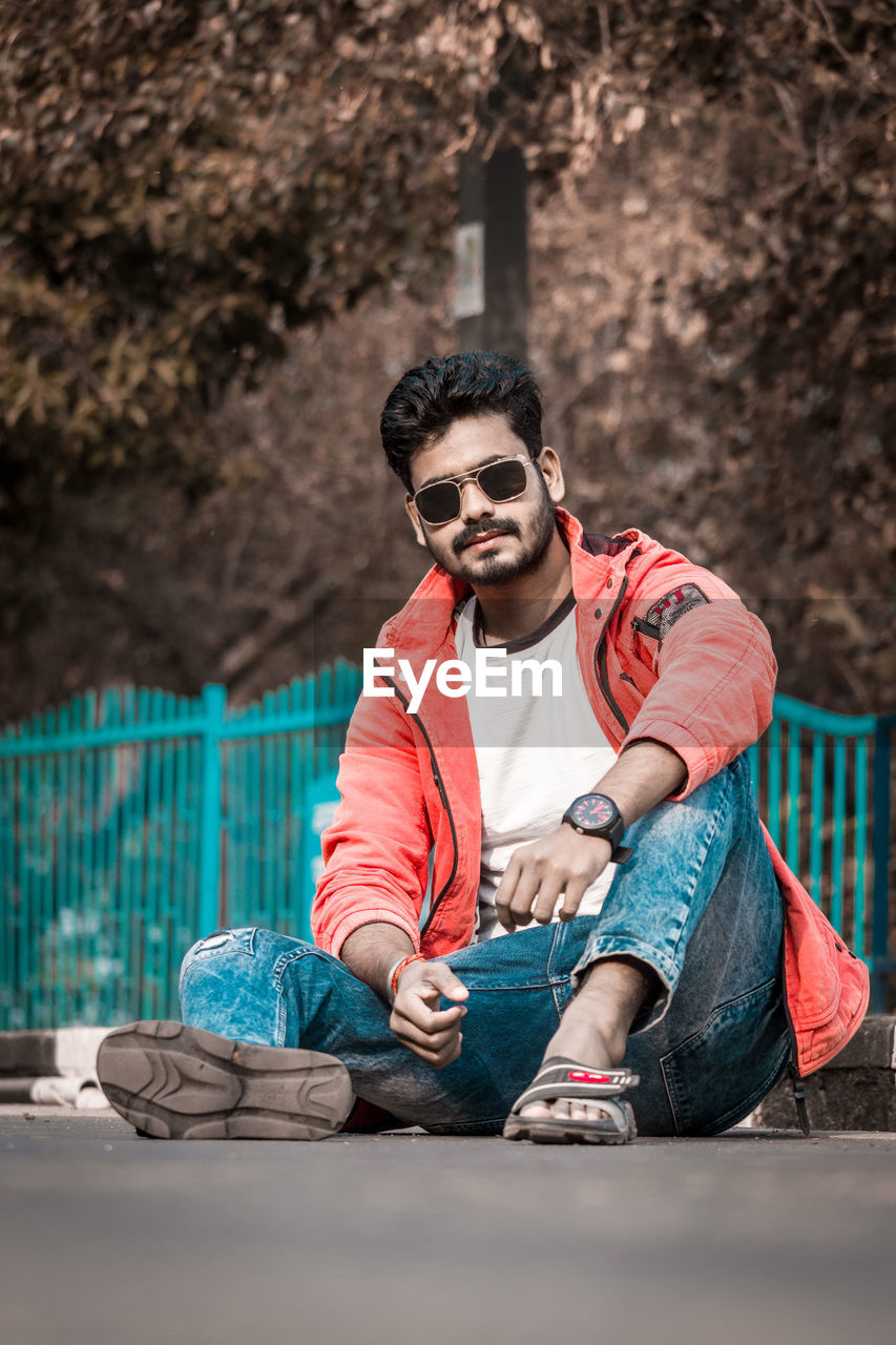 Portrait of young man wearing sunglasses sitting outdoors