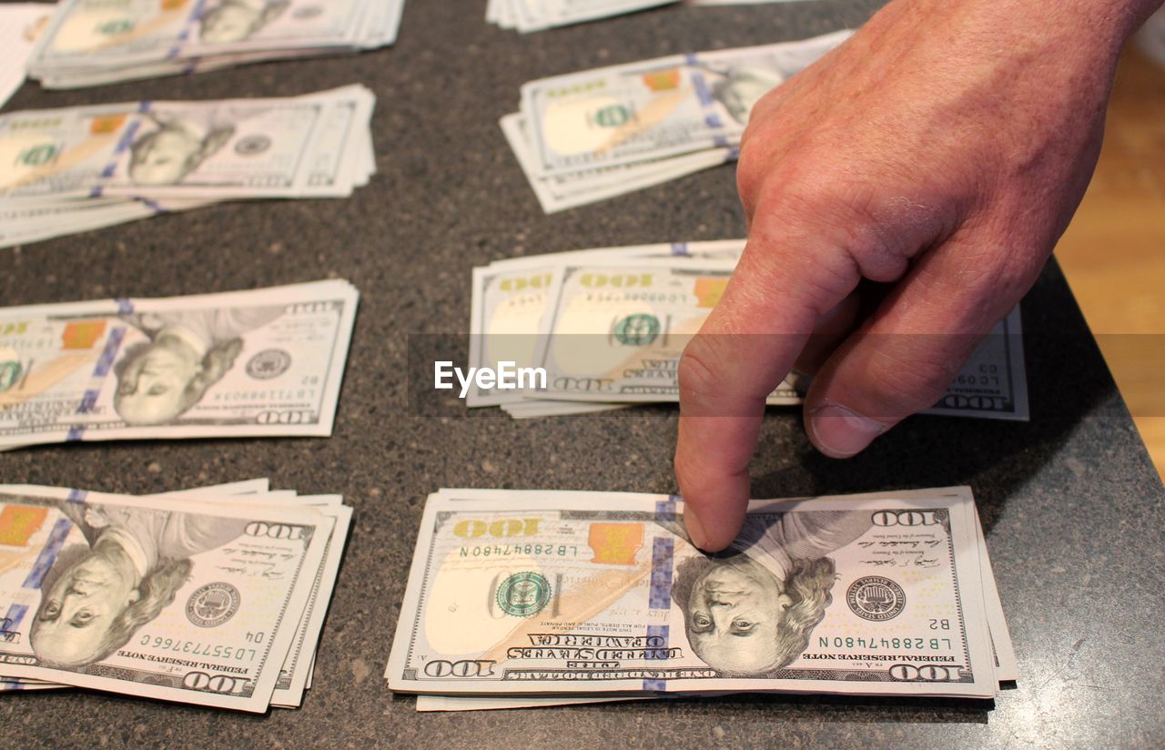 Cropped hand of person touching paper currency on table