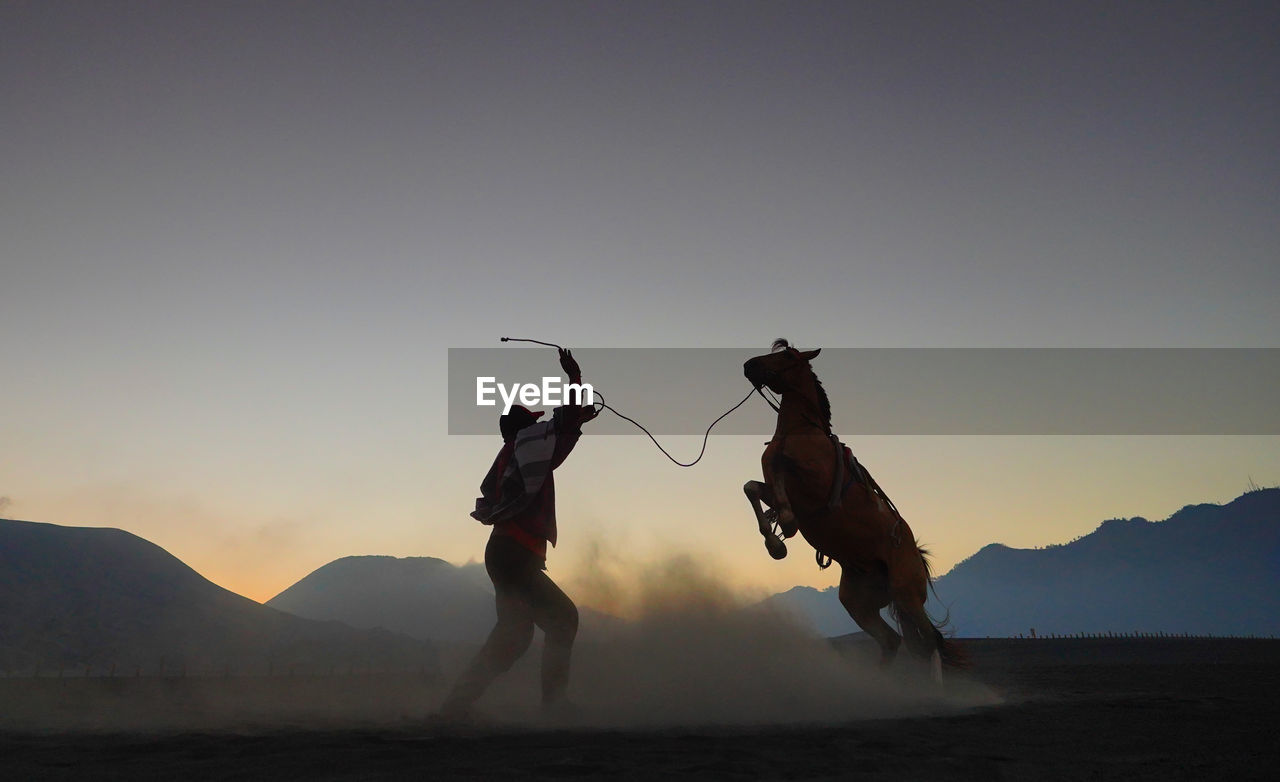 People on land against sky during sunset
