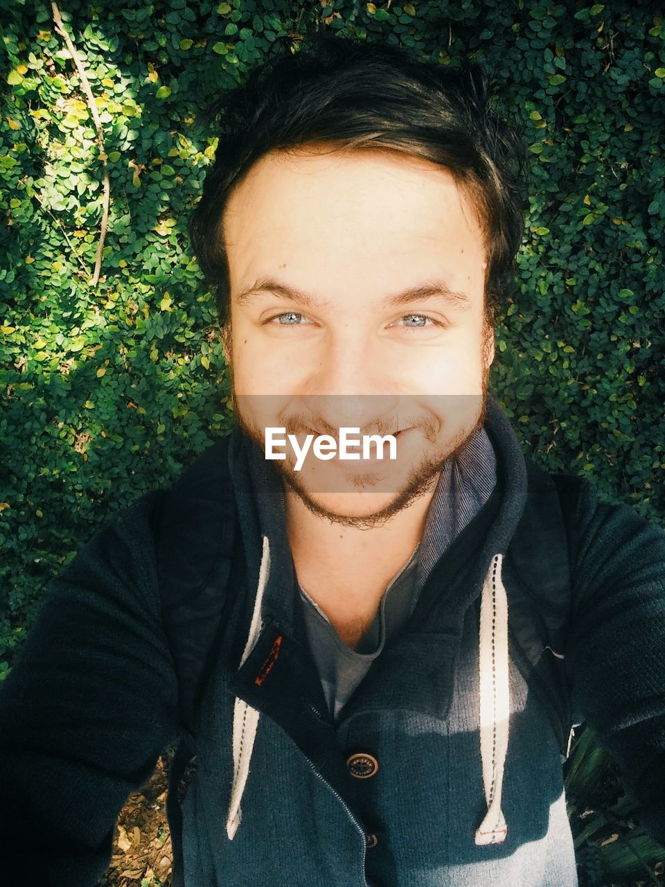 High angle portrait of man taking selfie while smiling against plants