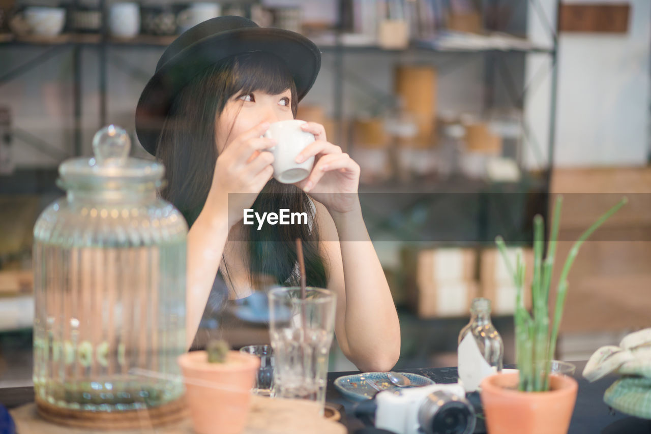 Women drinking coffee looking away while sitting at restaurant