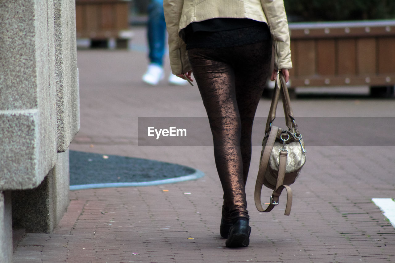 LOW SECTION OF WOMAN WALKING ON FOOTPATH