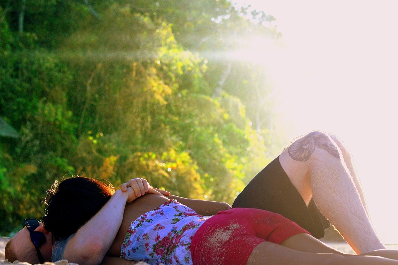 Couple lying on beach against bright sun