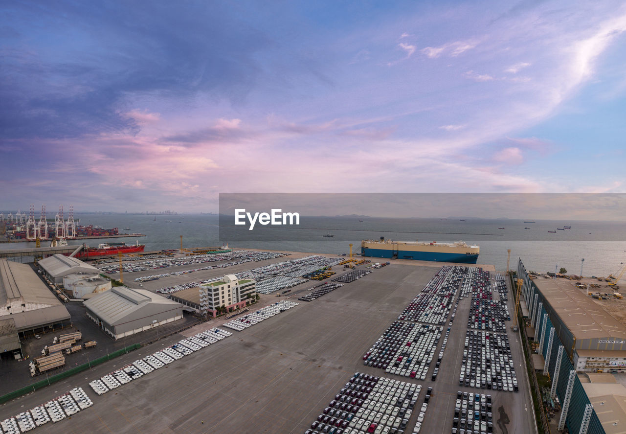 Aerial logistics commercial vehicles waiting to be load on to a car carrier ship at dockyard