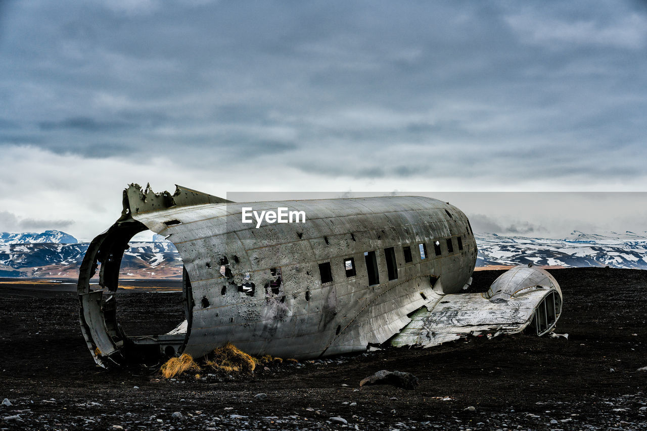 Crashed airplane on beach at solheimasandur against cloudy sky