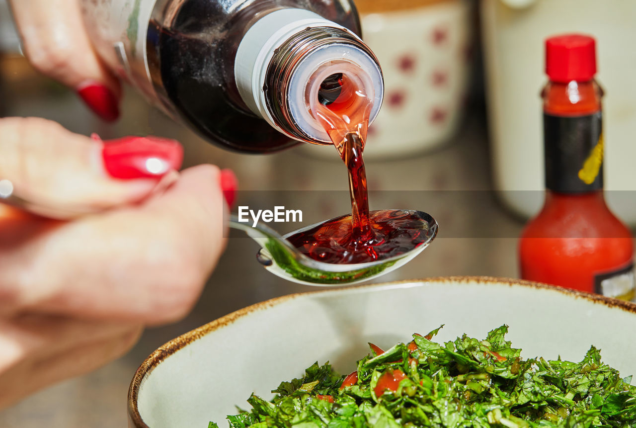 Chef pours pomegranate syrup with spoon to add to the salad.