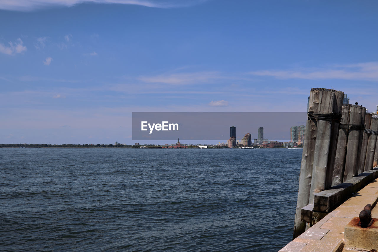 Sea by buildings in city against sky