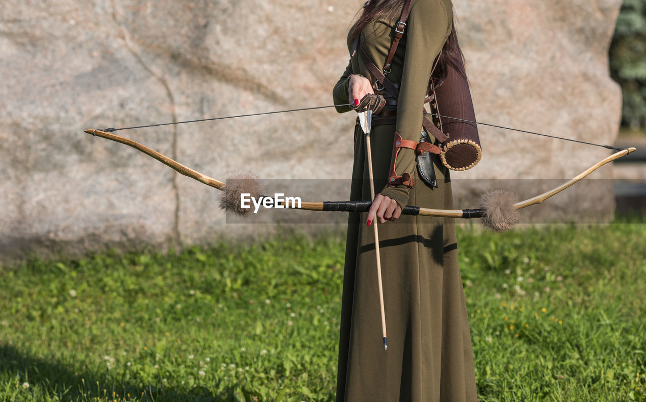 Midsection of woman holding archery while standing outdoors