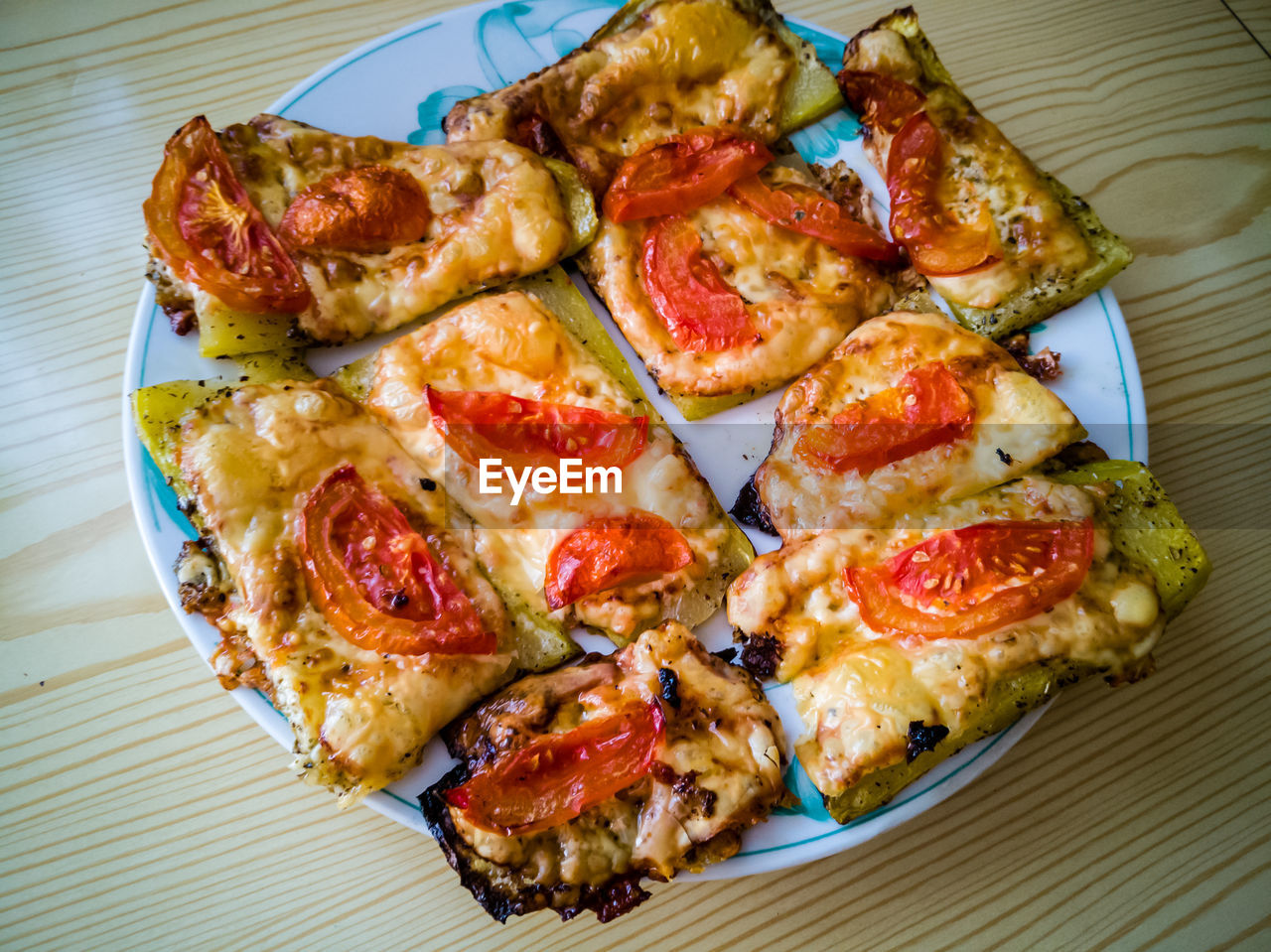 Zucchini on a plate with cheese and tomato prepared in a oven