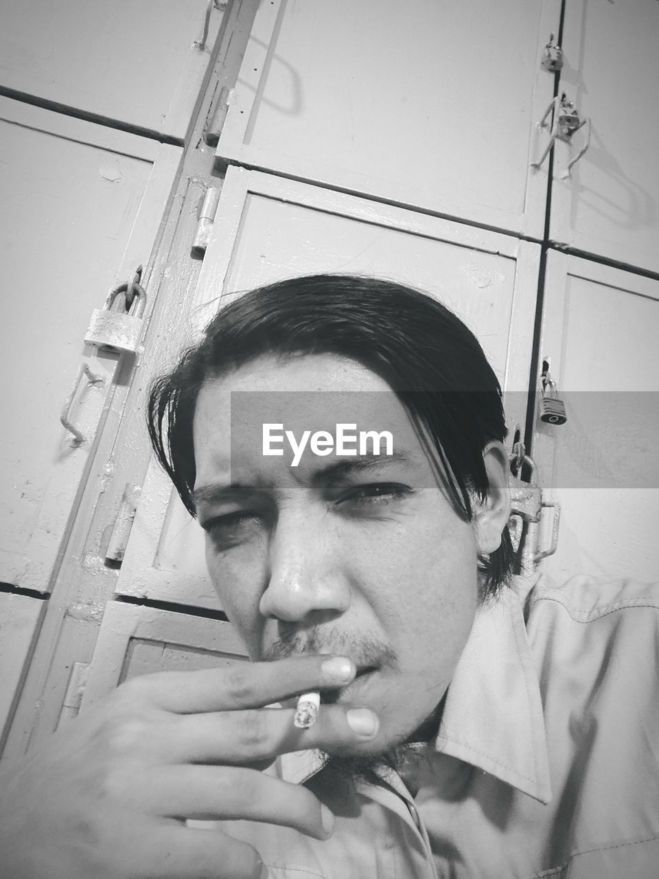 PORTRAIT OF YOUNG MAN SMOKING ON TABLE
