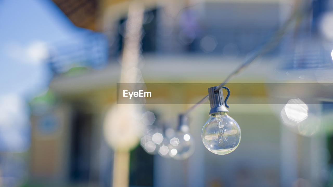 CLOSE-UP OF LIGHT BULB HANGING FROM GLASS