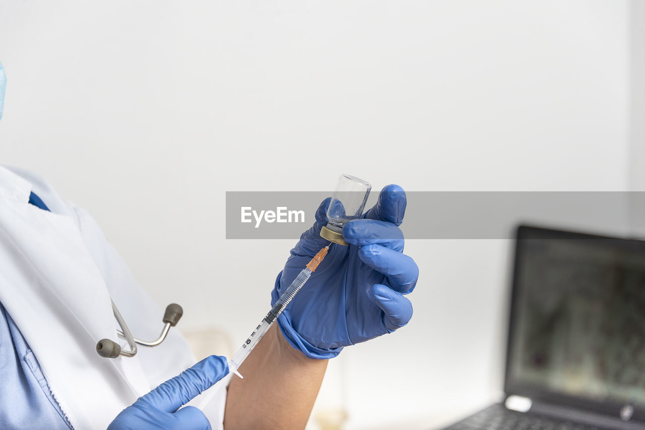 Hands of a doctor preparing a syringe to inject the vaccine for immunization to covid-19 