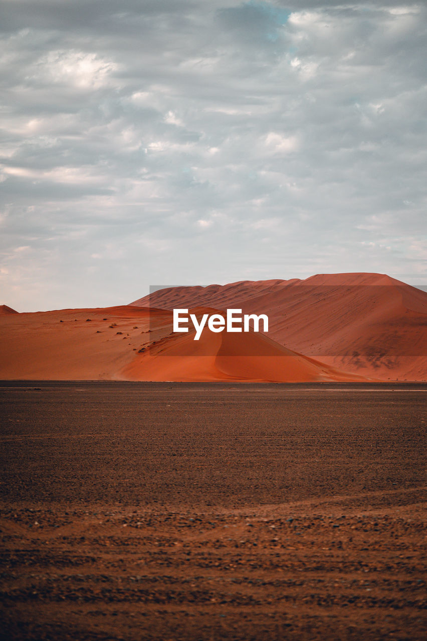 Scenic view of desert against cloudy sky