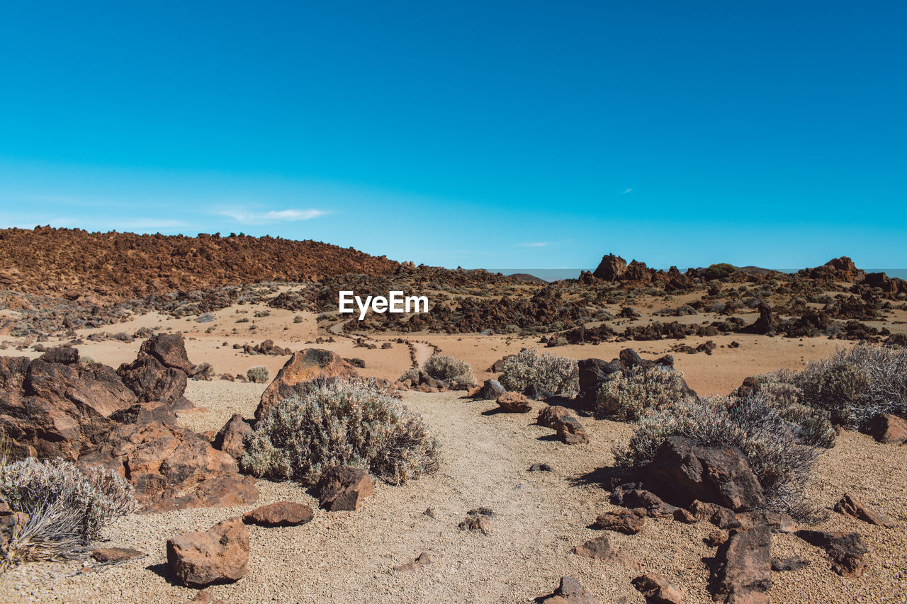 Scenic view of desert against blue sky