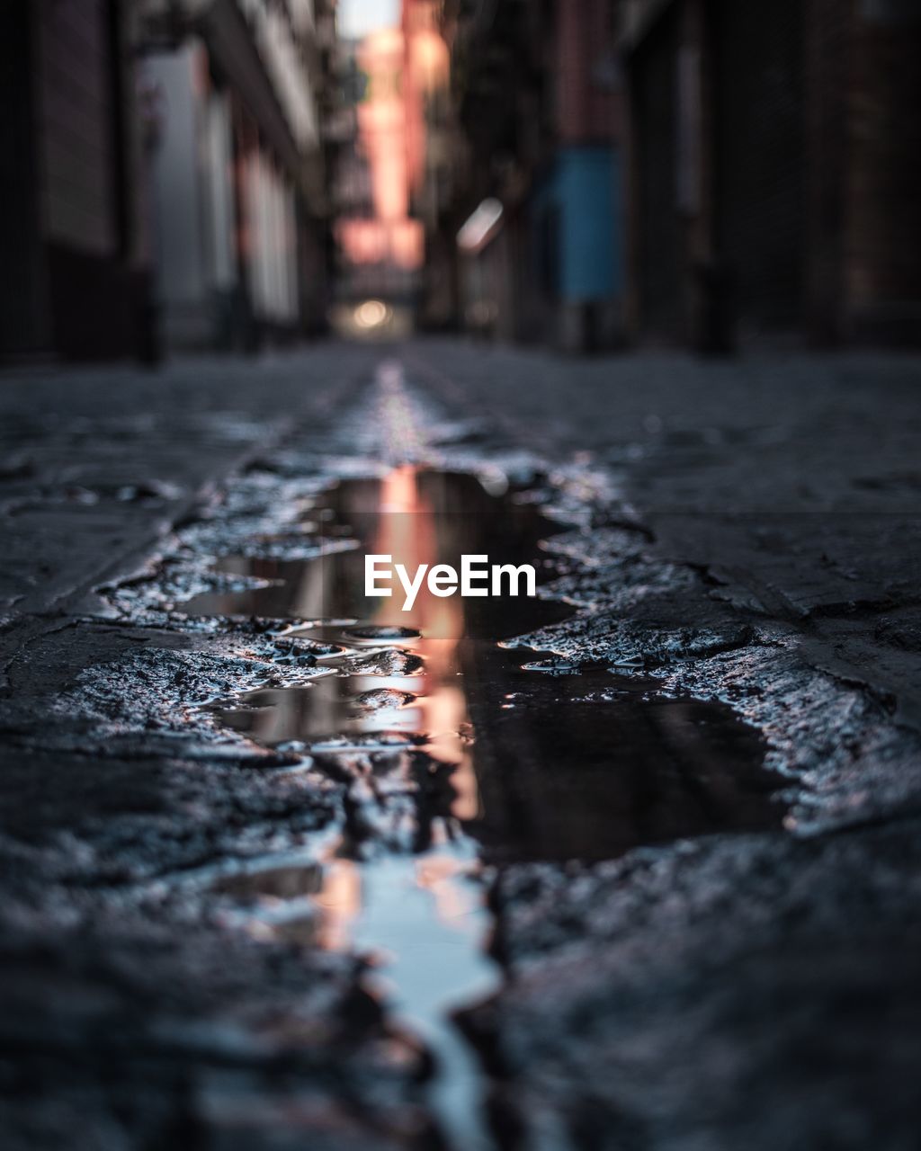 Surface level of puddle on road amidst buildings in city