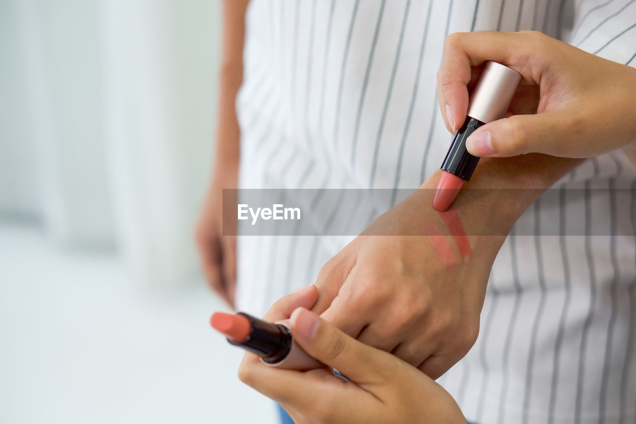 MIDSECTION OF WOMAN HOLDING SMART PHONE