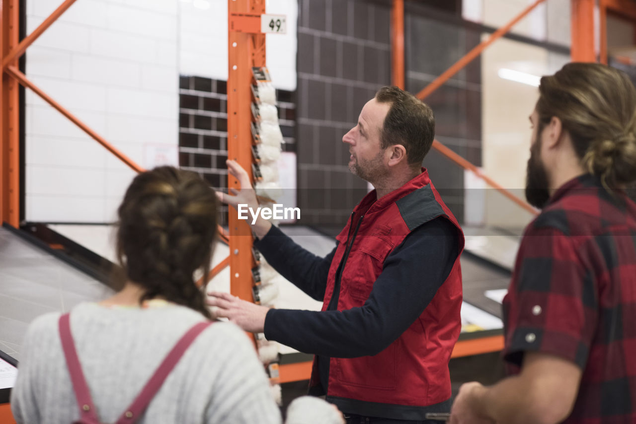 Salesman assisting couple in choosing tile at hardware store