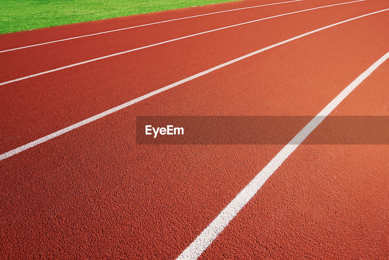 Red running track at stadium with border lanes