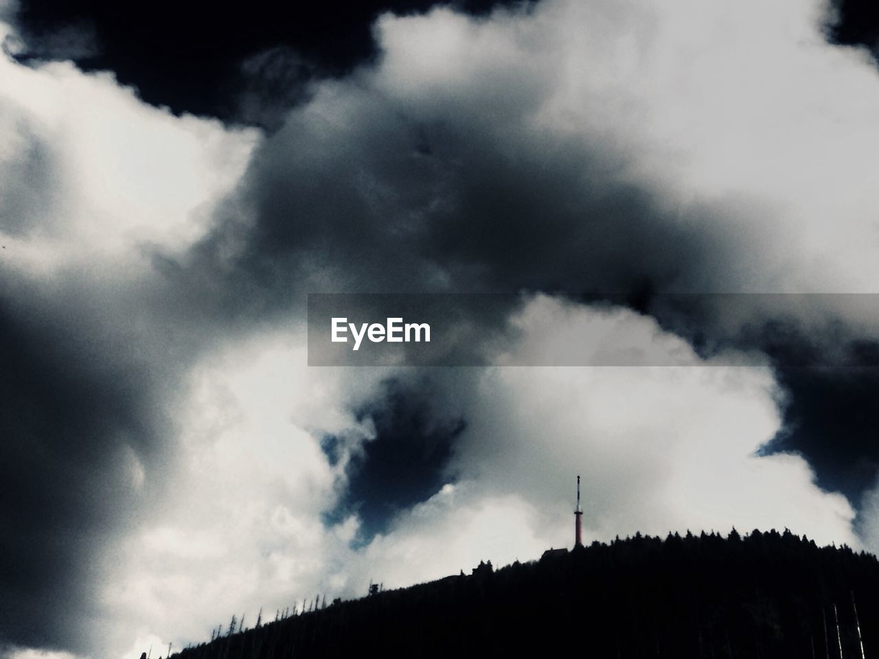 High section of silhouette landscape below cloudy sky
