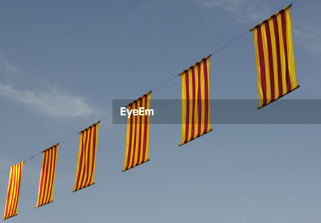 LOW ANGLE VIEW OF HANGING FLAGS AGAINST SKY