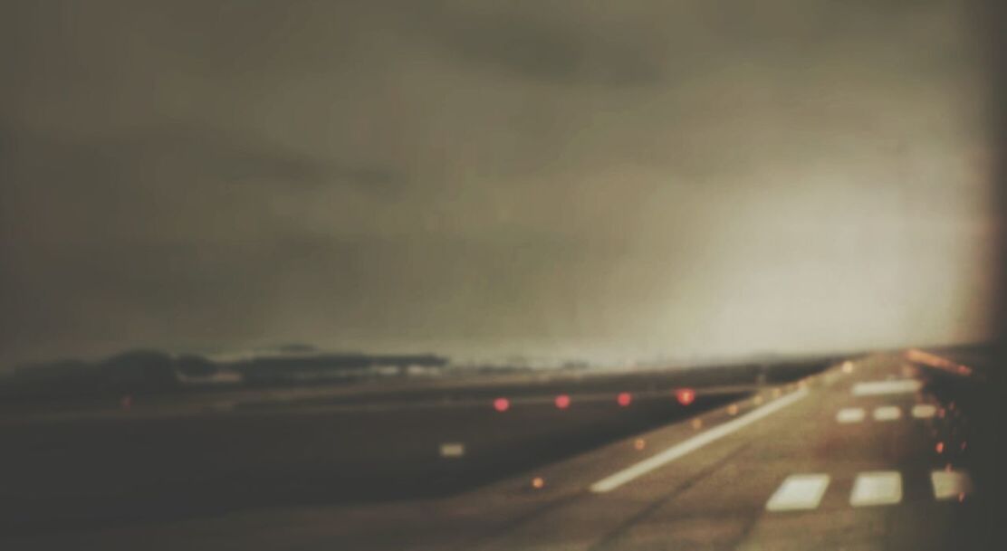 Defocused image of airport runway against cloudy sky during dusk