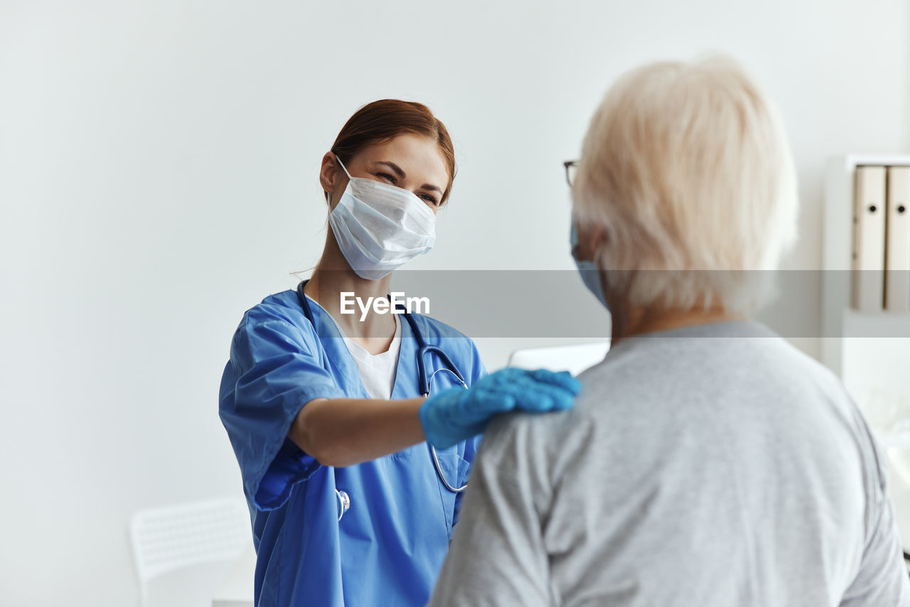 Doctor wearing mask talking to patient in hospital