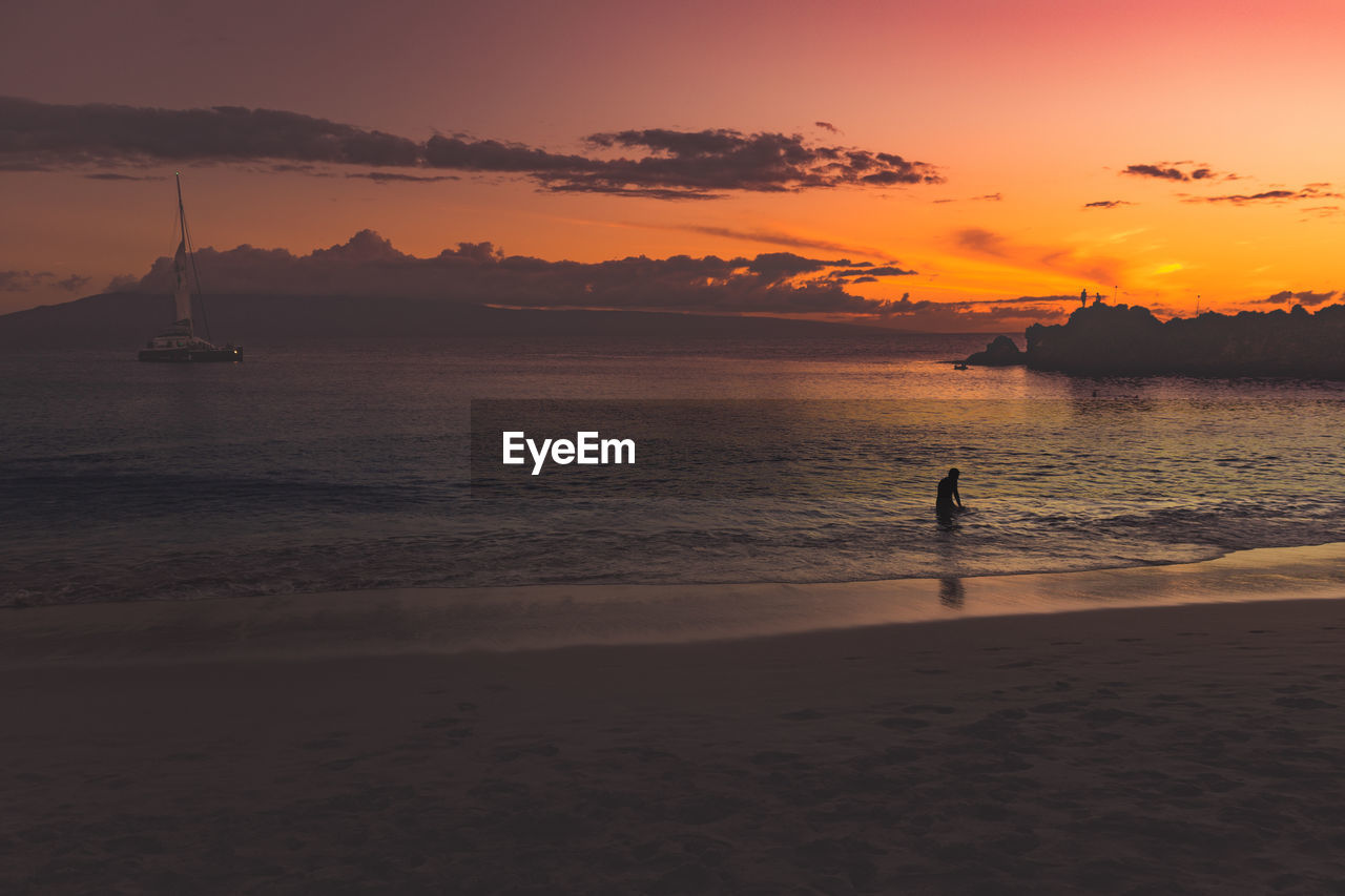 Scenic view of a person swimming in sea at dusk