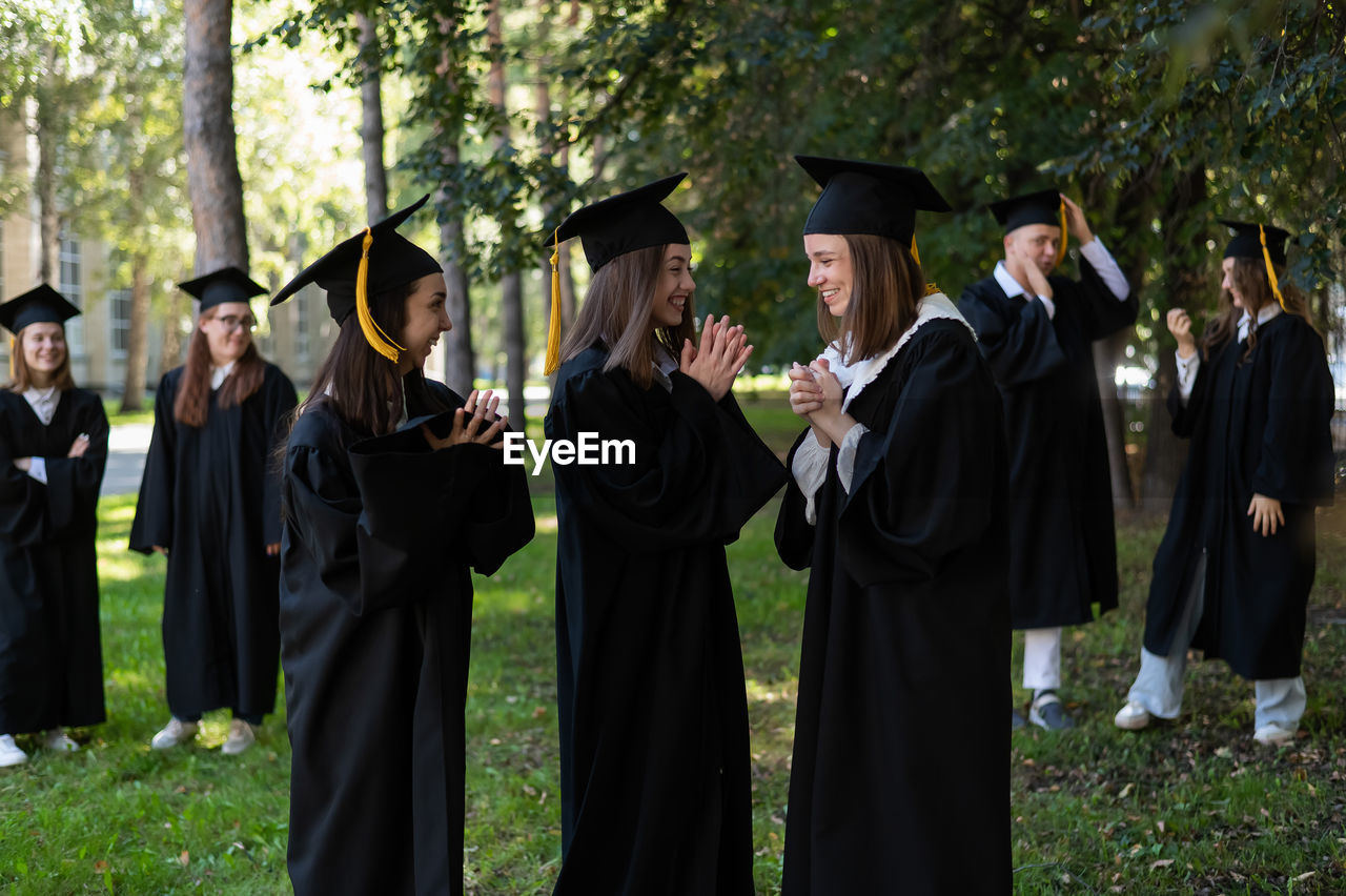 portrait of woman wearing graduation gown standing in park