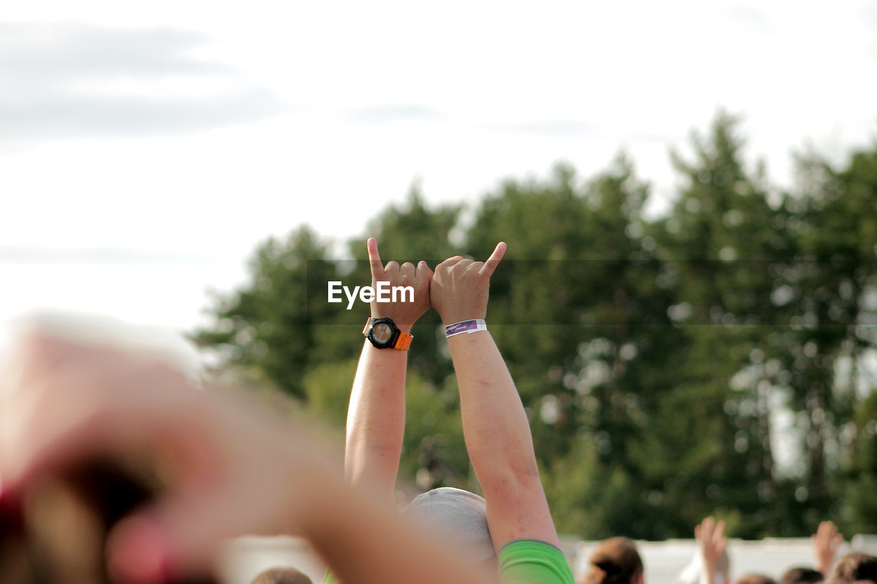 Cropped image of man with arms raised against sky