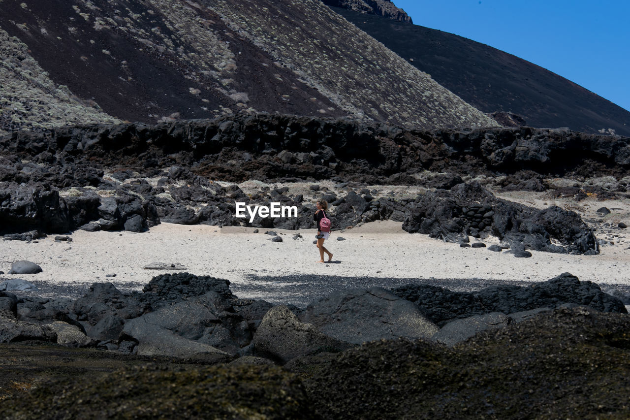 Person on rock against sky