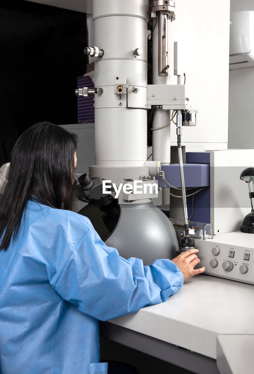 Young female scientist working at the laboratory with an electron microscope