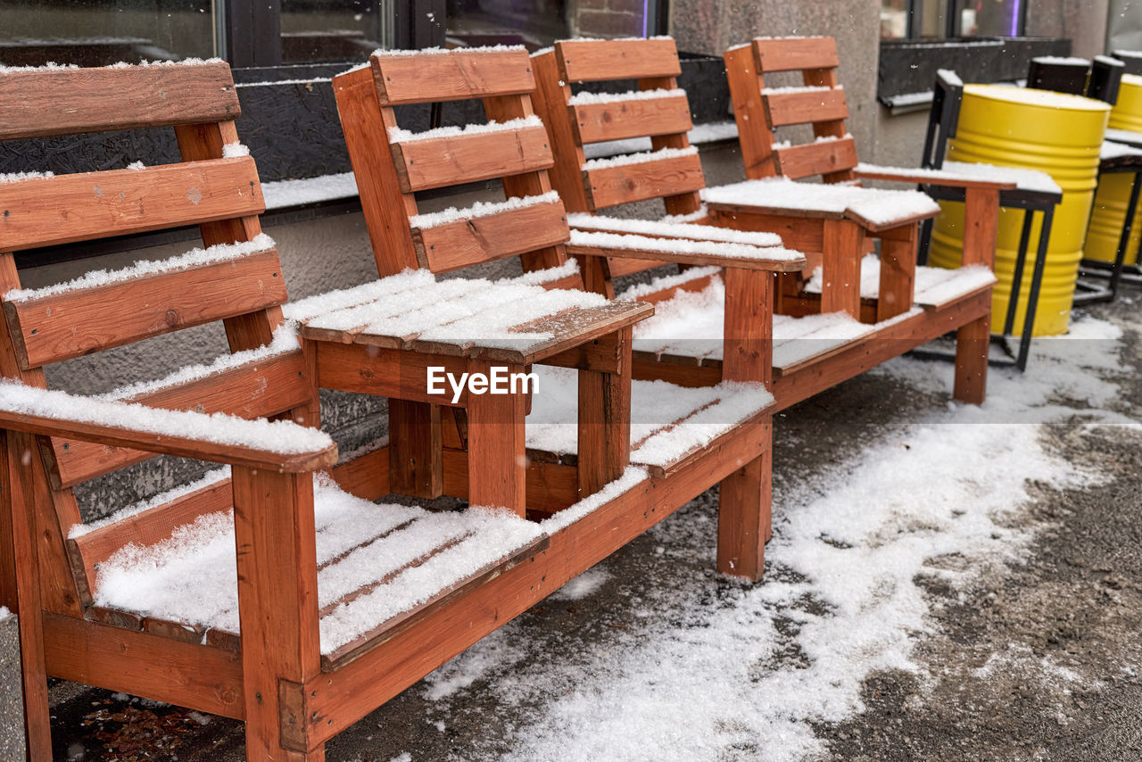 EMPTY CHAIRS AND TABLES IN WINTER AT OUTDOOR CAFE