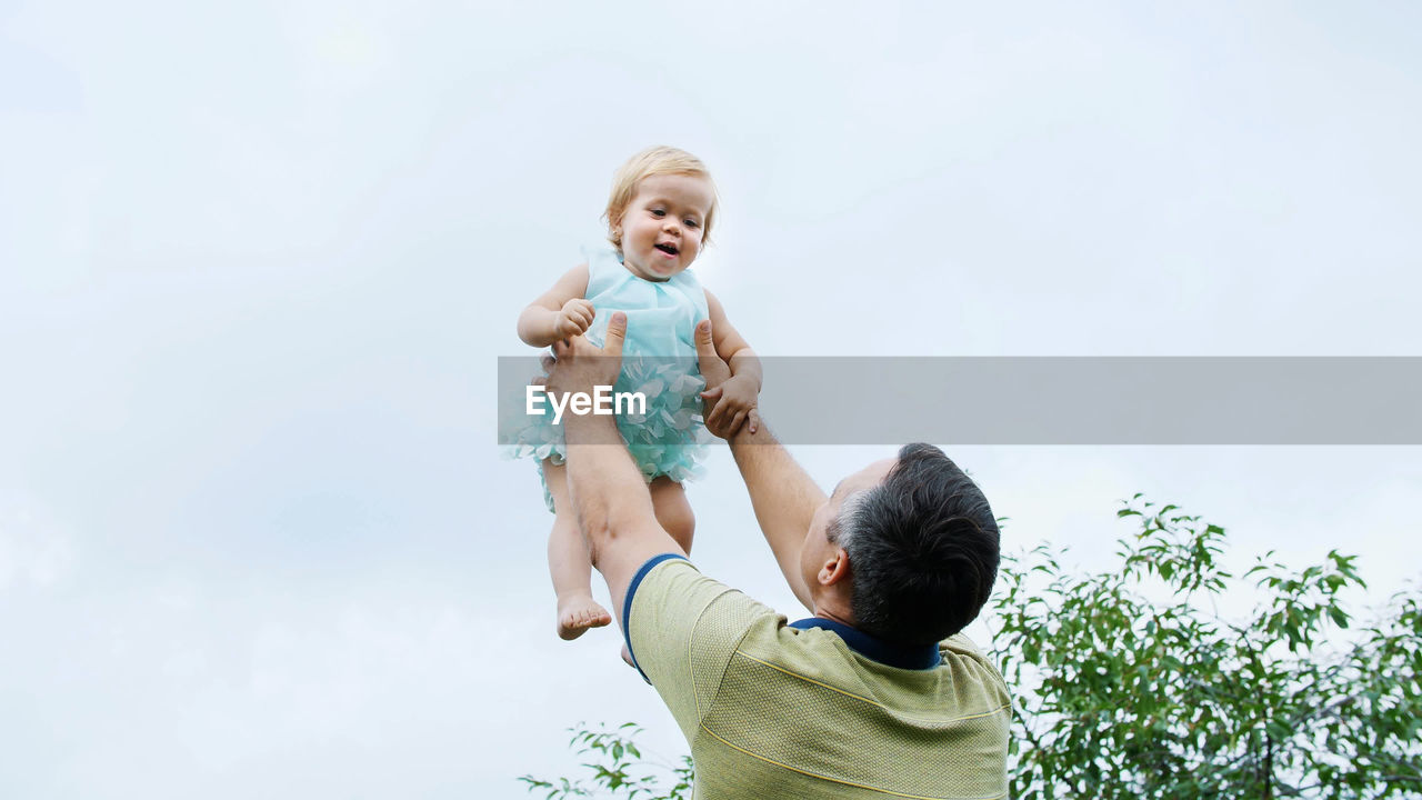 Summer, in the garden, mother, a view from below, the daddy throws his one-year-old daughter, plays
