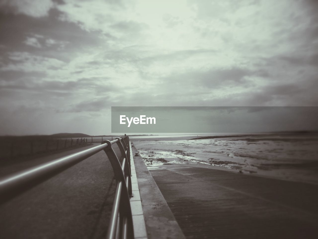 PIER OVER SEA AGAINST CLOUDY SKY