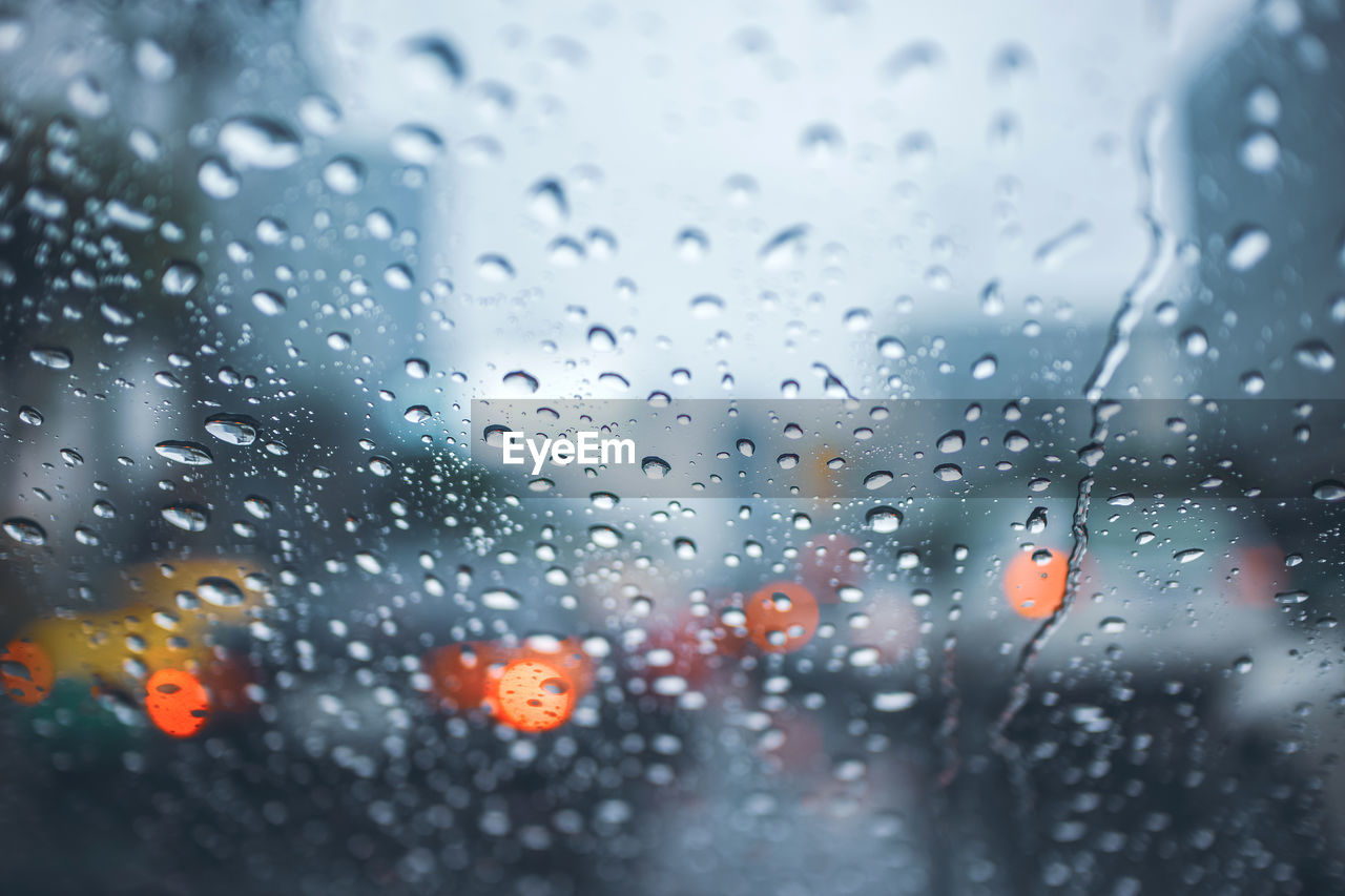 Driving car on road in the rain with raindrop over the wind shield, traffic jam in rainy season