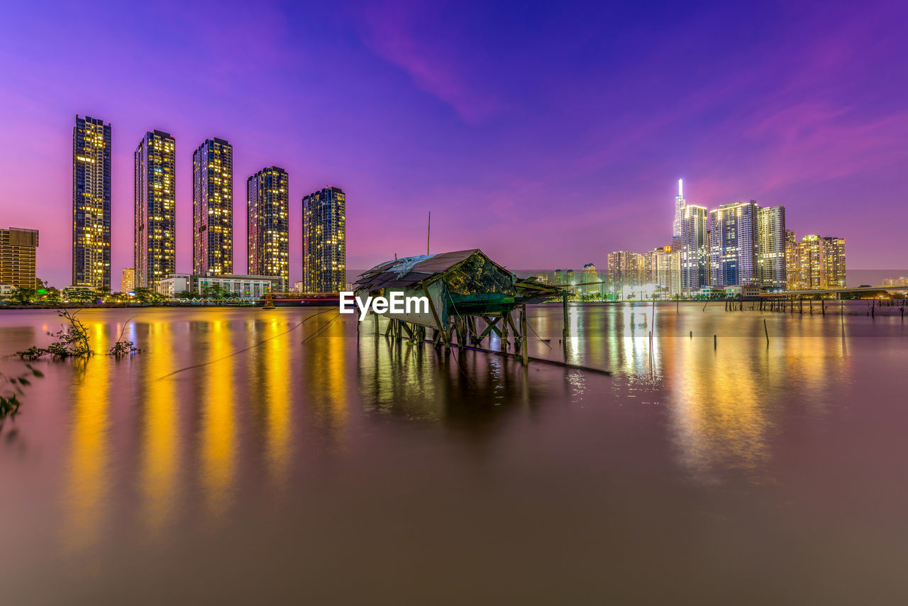 ILLUMINATED BUILDINGS IN CITY AT WATERFRONT