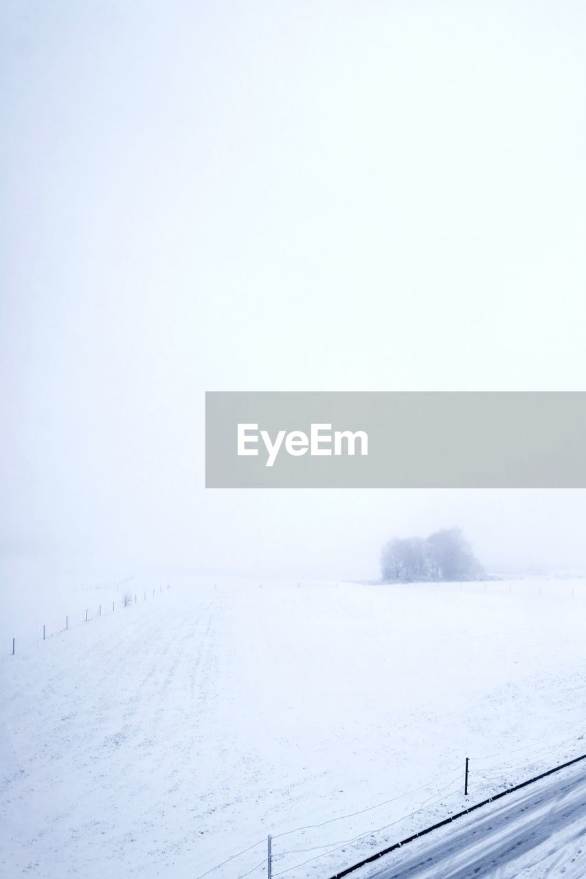 SCENIC VIEW OF SNOWY FIELD AGAINST CLEAR SKY DURING WINTER