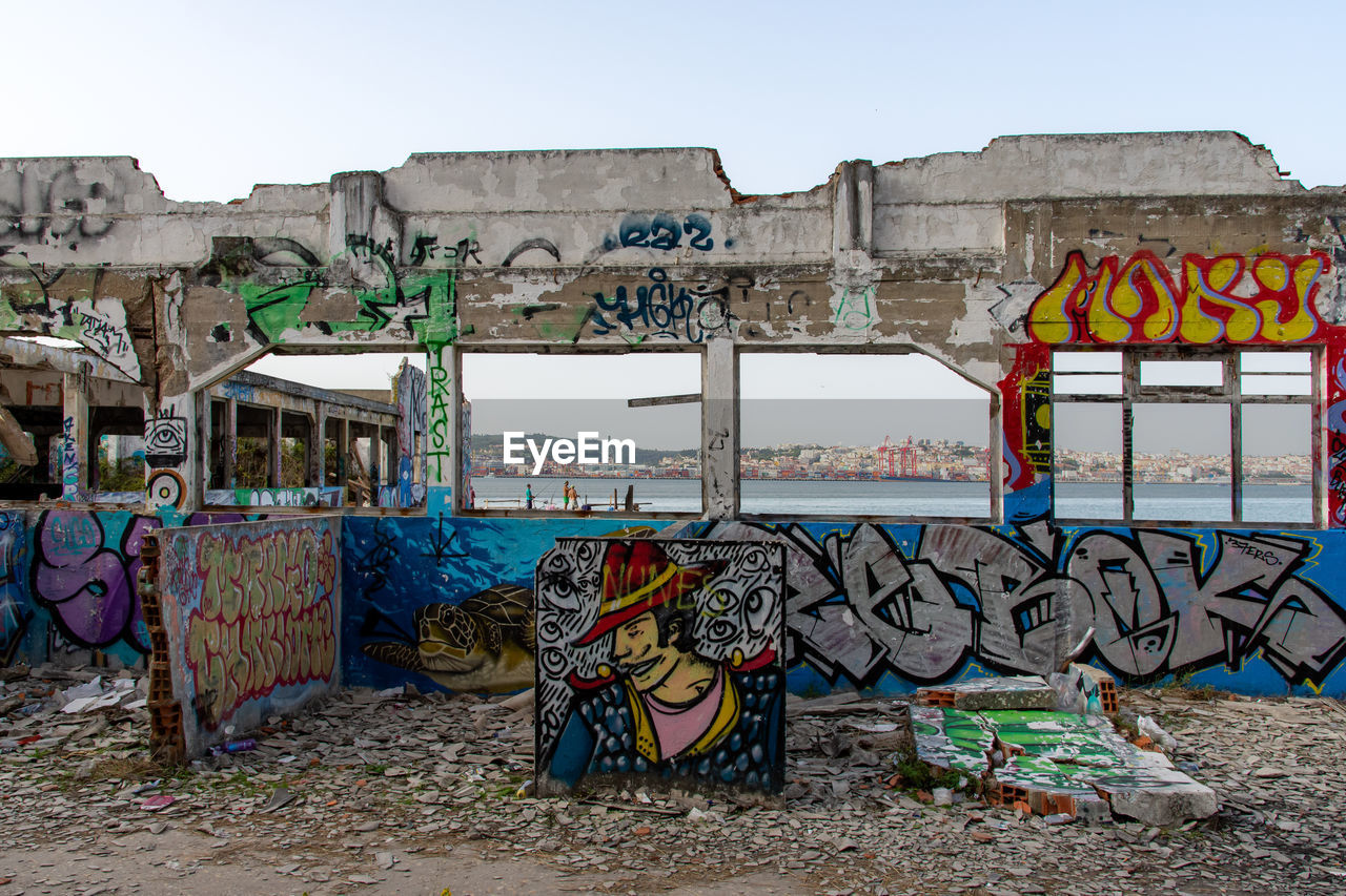 graffiti, architecture, art, urban area, street art, built structure, sky, creativity, multi colored, nature, no people, day, building exterior, outdoors, clear sky, city, building, vandalism, text, wall - building feature, mural