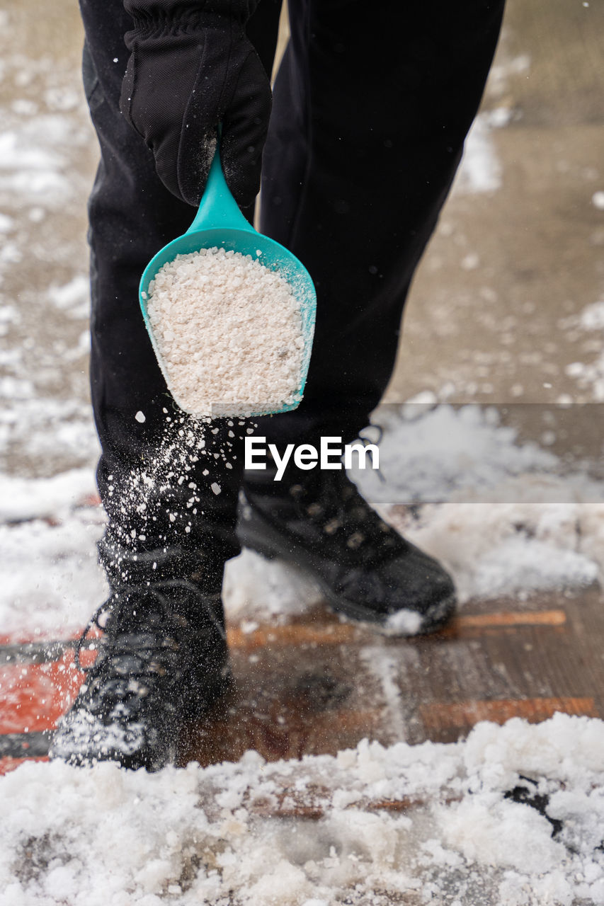 LOW SECTION OF PERSON STANDING AT SNOW