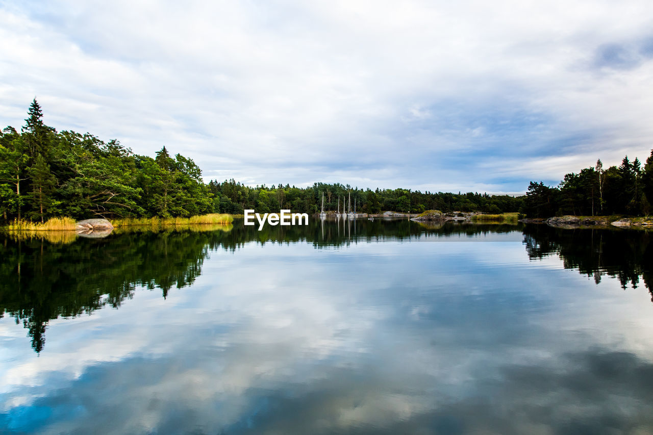 Scenic view of calm lake against cloudy sky