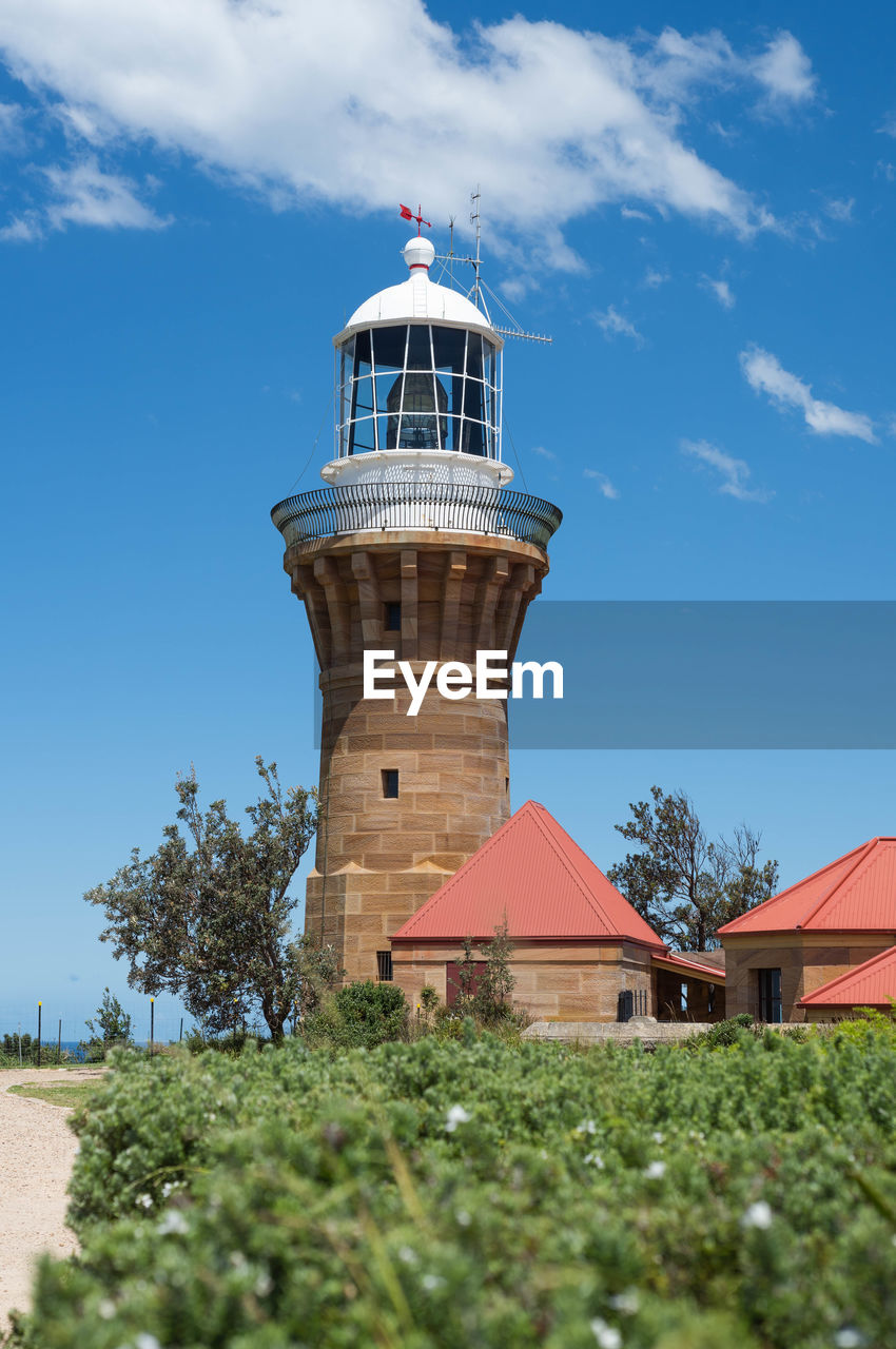 Low angle view of lighthouse by building against sky