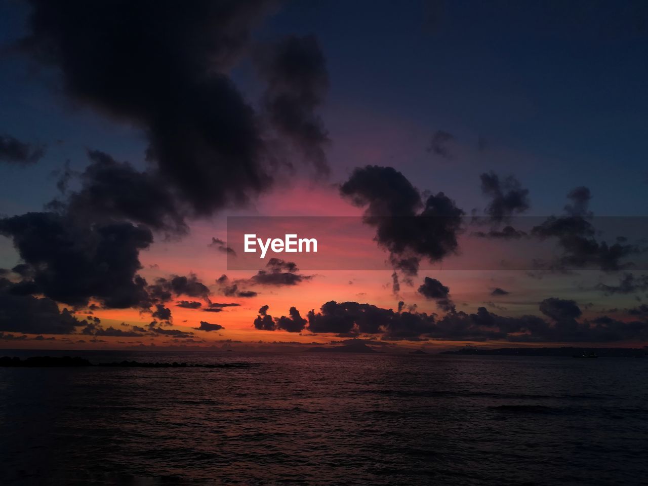 Scenic view of sea against dramatic sky during sunset