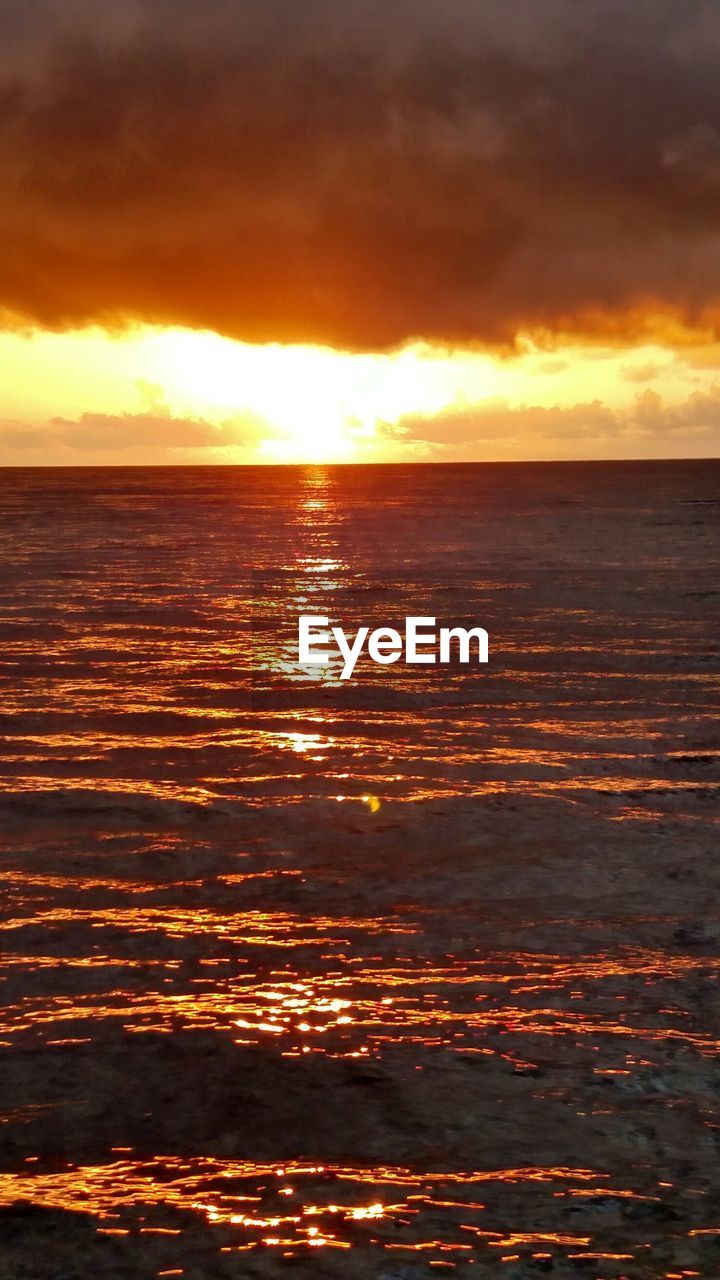 Scenic view of sea against cloudy sky at sunset