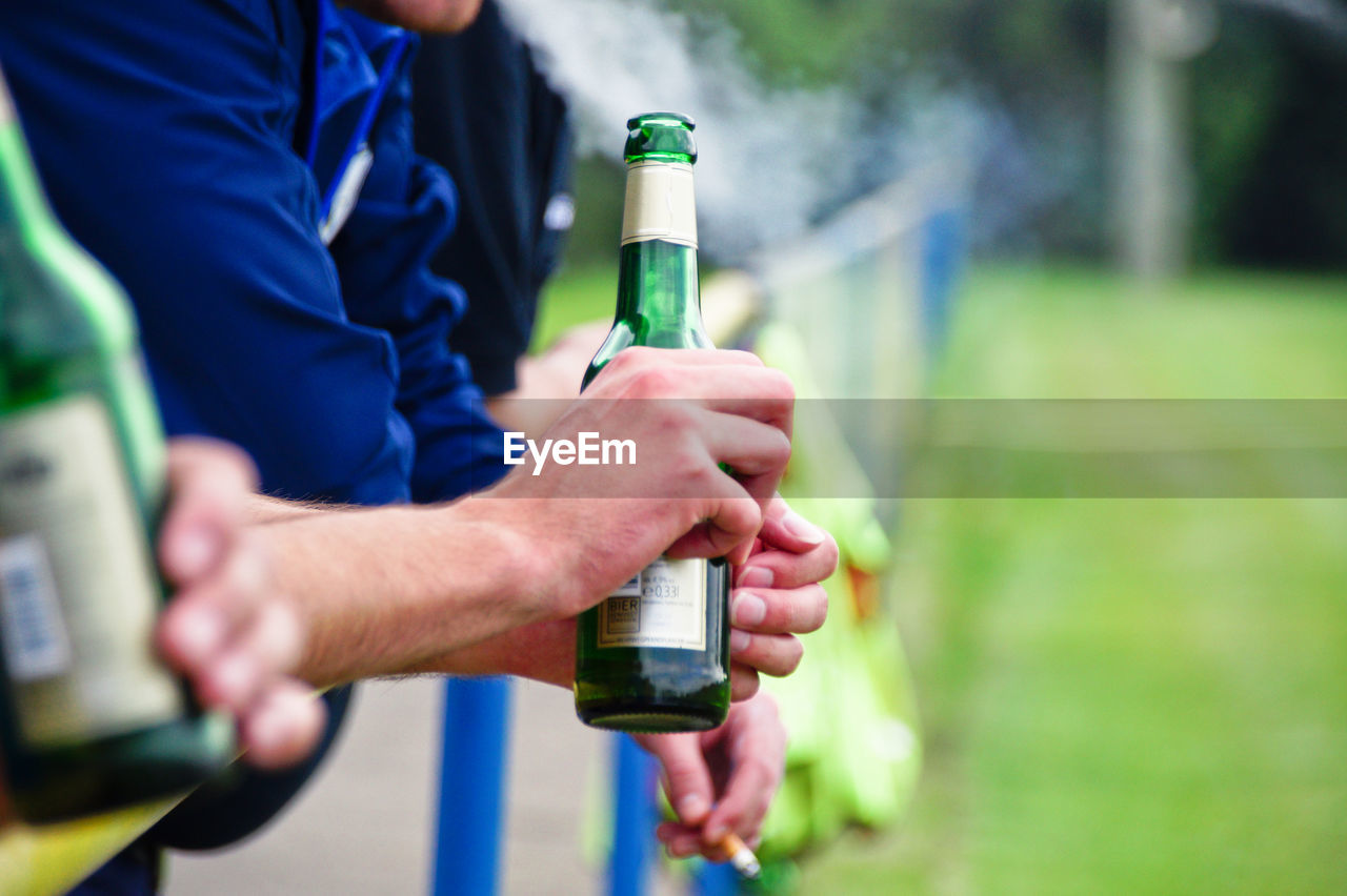 Midsection of man holding beer bottle